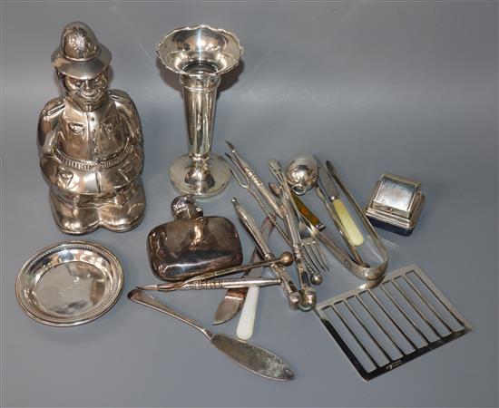 A group of mixed silver and plated items including a silver hip flask, silver spill vase and a plated Policeman money box.